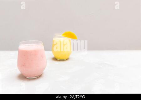 Traditional indian spiced drinks Mango lassi and Strawberry Lassi in glass cups on grey neutral background Stock Photo