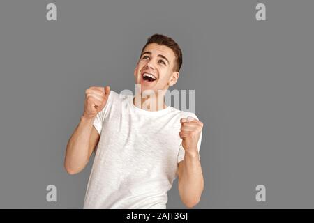 Copy Space for Text or Product. Young man standing isolated on grey looking up surprised Stock Photo