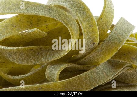 Italian green tagliatelle pasta with spinach, raw and uncooked. Basic ingredient in the recipe. Macro photography. Stock Photo