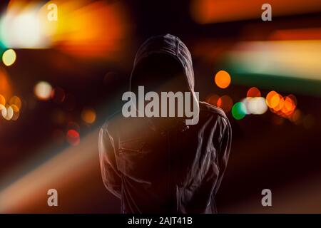 Hooligan with hoodie and obscured face walking the city streets at ...