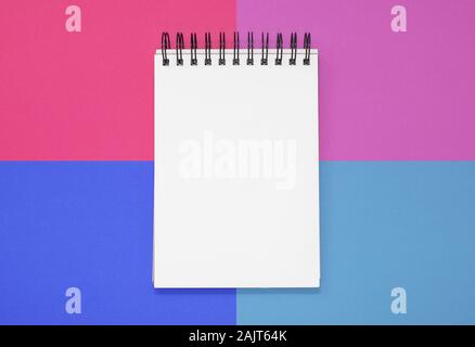 Open notepad on a pink and blue square background. Top view with copy space Stock Photo