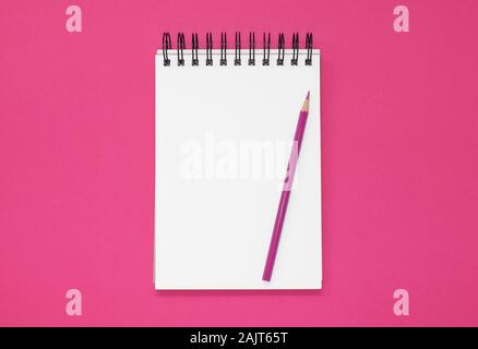 Open notepad and pencil on a hot pink background. Top view with copy space Stock Photo