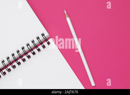 Open notepad and white pencil on a hot pink background. Top view with copy space Stock Photo