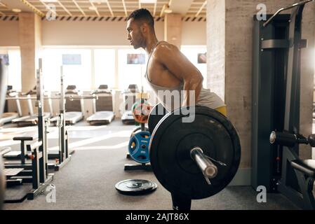 Athletic man doing exercise with barbell in gym Stock Photo