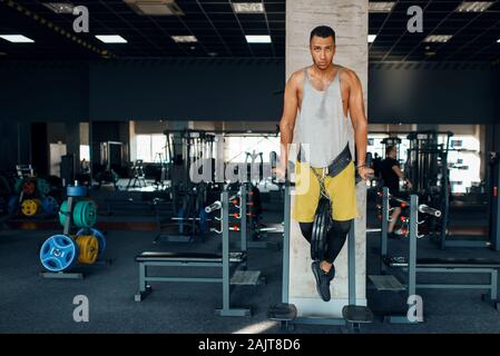 Athlete doing push ups on the uneven bars in gym Stock Photo