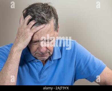 Head and shoulders portrait of a senior caucasian man with head in hands and looking depressed Stock Photo