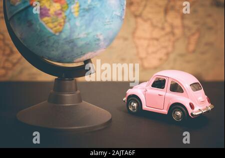 Vintage pink car and globe on a map background, close-up Stock Photo