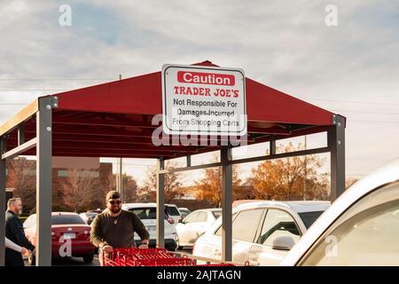 A man returns a Trader Joe's shopping cart to a cart park in Bradley Fair shopping center, Wichita, Kansas, USA. Stock Photo