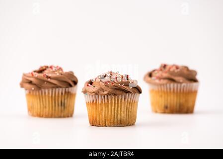 Delicious chocolate muffins, isolated on white background. Muffin and paper, sweet food or unhealthy eating theme. Stock Photo