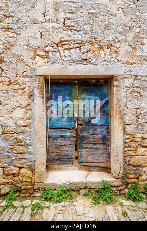 Colourful wooden doors in a doorway in a stone wall in the historic old town area in Bale, a small hill town on Mont Perin in Istria County, Croatia Stock Photo