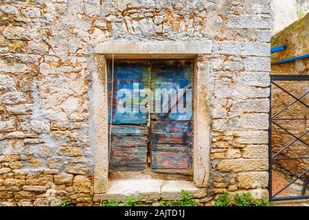 Colourful wooden doors in a doorway in a stone wall in the historic old town area in Bale, a small hill town on Mont Perin in Istria County, Croatia Stock Photo