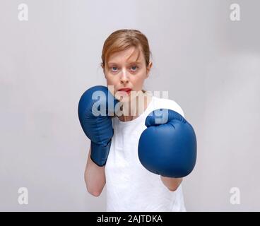 Young female boxer with blue boxing gloves during fight Stock Photo