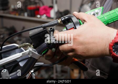 The master installs the plastic brake protection of the hand brake, as well as the clutch of the motorcycle. Replacing the pads on the levers. Motorcy Stock Photo