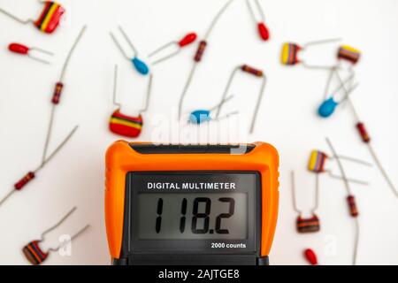 Digital multimeter showing a voltage reading surrounded by electronic components Stock Photo