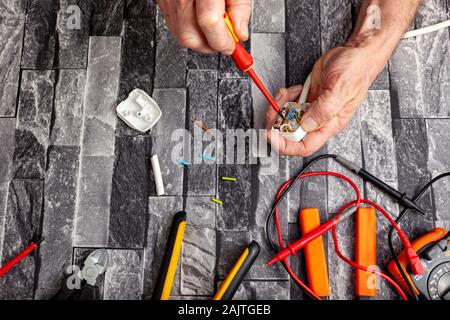 Electrical engineer using a screwdriver and fitting a 3 pin UK plug to a white appliance cable Stock Photo