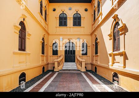 JAN 13, 2019 Udon Thani, Thailand - Grand historic Yellow French Colonial building artisan window and door frames with classic entrance courtyard of U Stock Photo