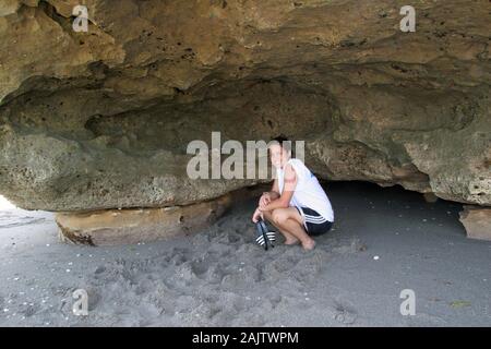 Young woman explores the Anastasia limestone outcroppings in Blowing Rocks Preserve on Jupiter Island, Florida on clear cloudless afternoon. Stock Photo