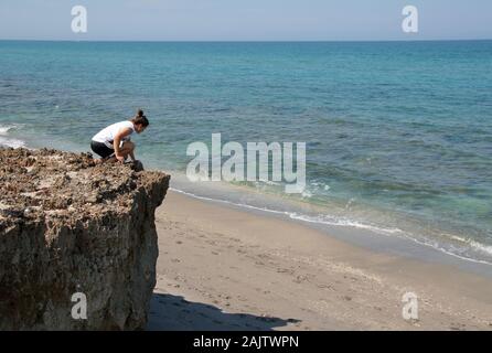 Young woman explores the Anastasia limestone outcroppings in Blowing Rocks Preserve on Jupiter Island, Florida on clear cloudless afternoon. Stock Photo