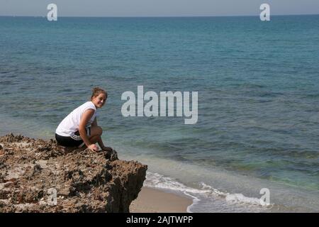 Young woman explores the Anastasia limestone outcroppings in Blowing Rocks Preserve on Jupiter Island, Florida on clear cloudless afternoon. Stock Photo