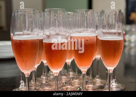 Lined crystal flutes filled with champagne on black granite counter for gold anniversary celebration. Toast of the 50 years of marriage. Golden weddin Stock Photo