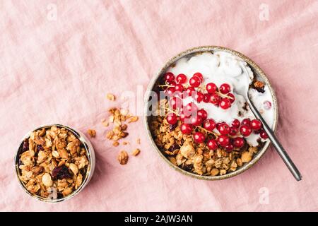 Homemade granola with greek yogurt and red currant berries on pink background. Top view of healthy breakfast food. Copy space Stock Photo