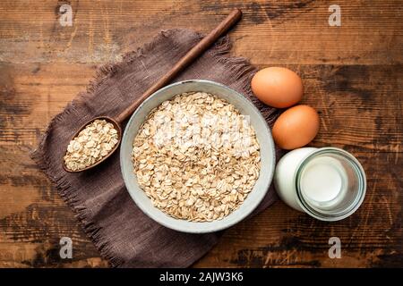 Milk, eggs and oat flakes on old wooden table background. Top view. Healthy food, dieting concept Stock Photo