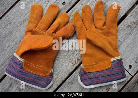 Pair of work gloves made from cheap leather with textile extensions around wrists. Stock Photo