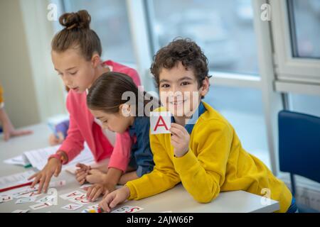 Smiling schoolboy holding a card with the letter A Stock Photo