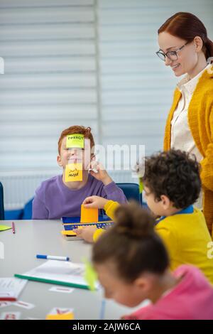 Smiling teacher helping pupils playing vocabulary game Stock Photo
