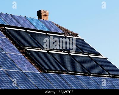 combination roof installed photovoltaic PV solar panels and solar water heater pipe system on brown sloped clay roof . sun collector water pipe heater Stock Photo