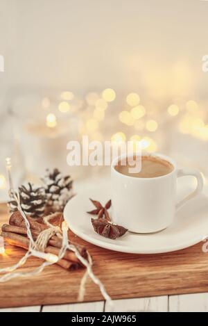 Cup of coffee with garland lights and decoration on table. Cozy home concept Stock Photo