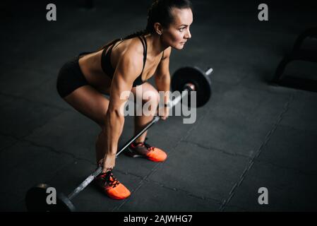 Strong woman bodybuilder preparing to lift the heavy barbell from the floor Stock Photo
