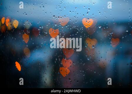 Heart-shaped city lights through window glass with raindrops Stock Photo