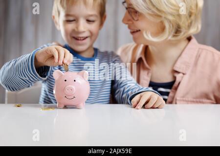 three years old child sitting st the table with money and a piggybank Stock Photo