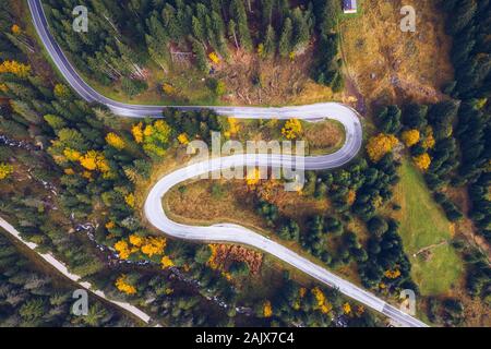 Curved bending road in the forest. Aerial image of a road. Forrest pattern. Scenic curvy road seen from a drone in autumn. Aerial top down view of zig