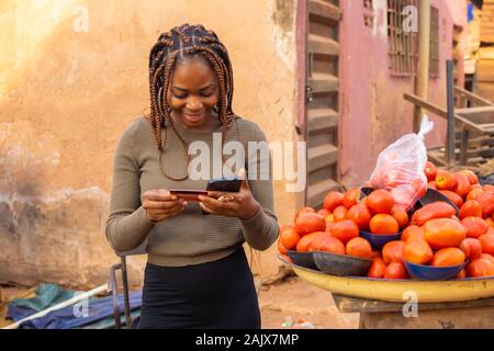 young black lady using her smartphone and credit card to purchase something in the market Stock Photo