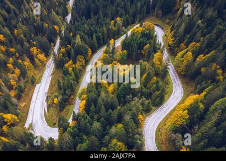 Curved bending road in the forest. Aerial image of a road. Forrest pattern. Scenic curvy road seen from a drone in autumn. Aerial top down view of zig
