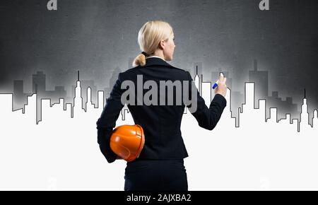 Businesswoman draws silhouette of business center Stock Photo