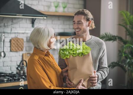 Young man with package of greens smiling to his mom Stock Photo