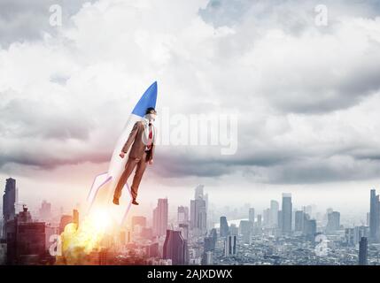 Business person in aviator hat flying on rocket Stock Photo