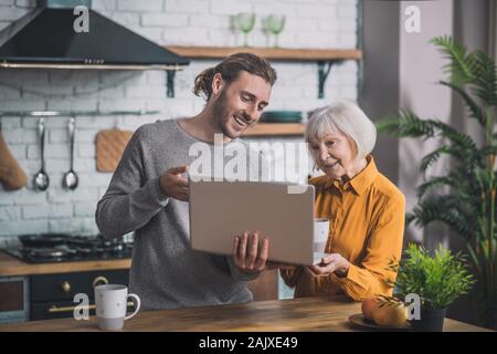 Grey-haired mom and her son checking online shop Stock Photo
