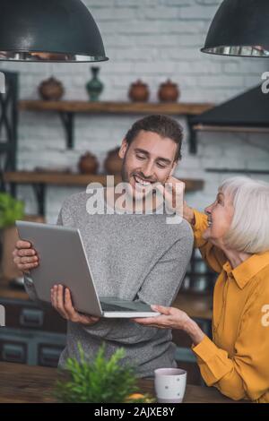 Grey-haired mom touching her sons cheek tenderly Stock Photo