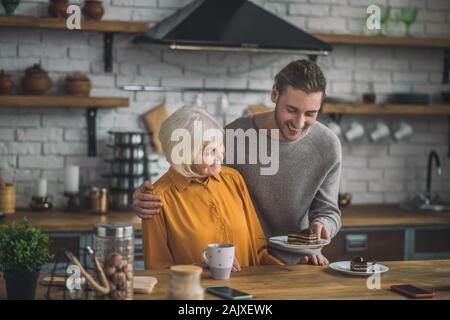 Mom in yellow shirt and her son having fun together eating chocolate dessert Stock Photo