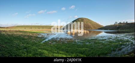 The huge Neolithic chalk mound of Silbury Hill, Avebury, Wiltshire, UK, reflected in a flooded meadow. It is 40m high and was built around 2300 BC Stock Photo