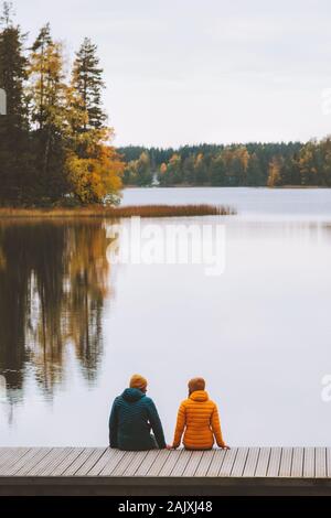 Couple in love family travel lifestyle relationship man and woman friends sitting on pier outdoor enjoying lake and forest landscape autumn season har Stock Photo