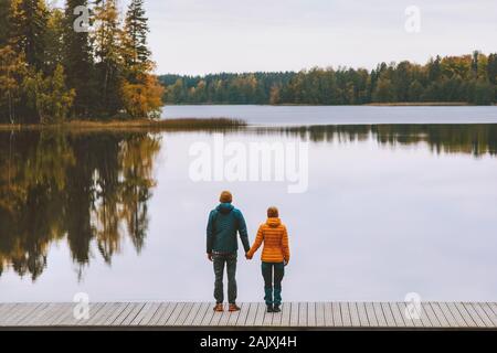 Couple in love holding hands romantic dating family lifestyle relationship man and woman standing on pier outdoor enjoying lake and autumn forest land Stock Photo