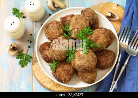 Homemade meatballs with mushrooms on the kitchen wooden table. Stock Photo