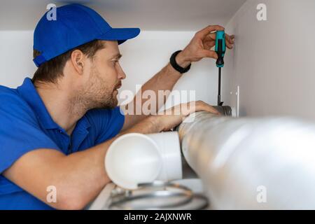 hvac technician repairing flexible aluminum tube for house ventilation system Stock Photo