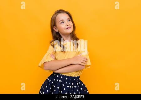 Pretty little girl in beautiful dress rejoices of her life isolated on orange background Stock Photo