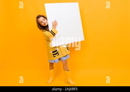 Download Beautiful Girl In A Raincoat Holds A Billboard With A Mockup On A Yellow Background With Copy Space Stock Photo Alamy